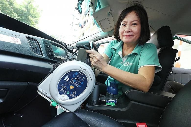 HDT taxi driver Vicky Lim with an automated external defibrillator. Sponsorship from the Singapore Heart Foundation has allowed the cab company to fit 50 of its taxis with the portable device, which can send an electric shock to the heart to revive i
