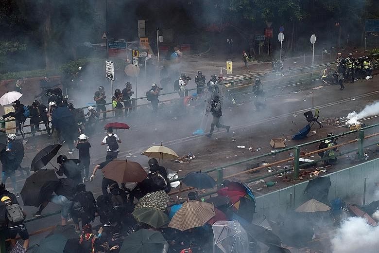 Above: People fleeing from tear gas while trying to re-enter the PolyU campus after a failed attempt to leave during clashes with police. PHOTO: REUTERS Right: Young people detained by police near the PolyU campus in Hong Kong's Hung Hom district. PH