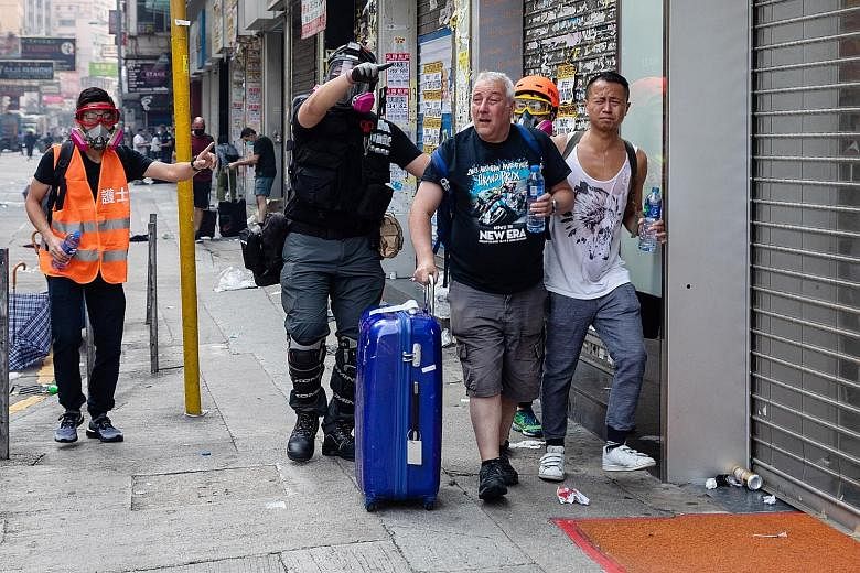 Right: Passers-by affected by tear gas during clashes between police and protesters in the Tsim Sha Tsui district yesterday. PHOTO: BLOOMBERG