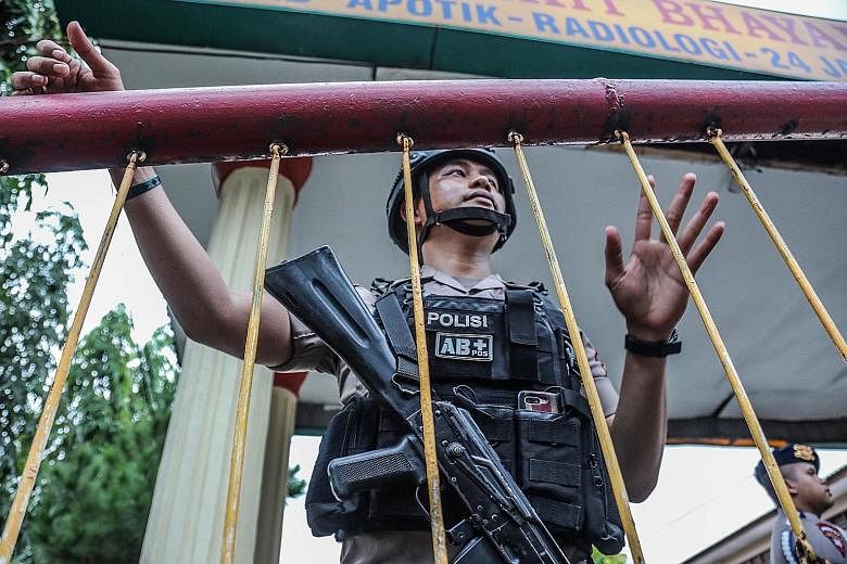 A member of the Indonesian Mobile Brigade Corps guarding the entrance to its headquarters following the killing of the two bomb-makers in a raid last Saturday in Medan, North Sumatra. One police officer was hurt during the raid.