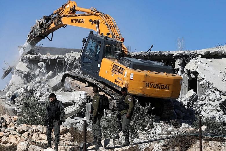Israeli troops standing guard as bulldozers demolished two houses near Arroub refugee camp north of the West Bank city of Hebron, yesterday. Israel on a regular basis demolishes Palestinians' houses in the West Bank citing missing building permits. P