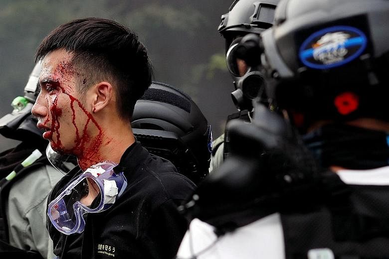 Police detaining an injured protester at the campus of Hong Kong Polytechnic University on Monday. The violence by both sides in Hong Kong has rapidly escalated, say the writers. And responsibility for the escalation lies mainly with the government a