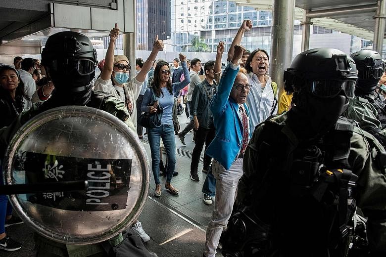 Riot police on the alert as pro-China supporters shouted slogans and gestured towards office workers (not seen in picture) who had gathered in support of pro-democracy protesters yesterday during a lunchtime rally in Hong Kong's Central district.