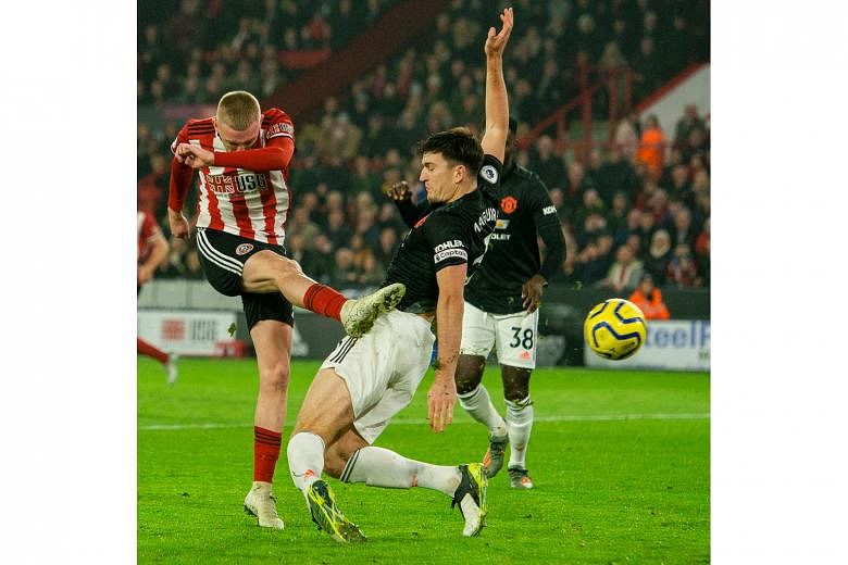 Sheffield United's Oli McBurnie beating Manchester United defender Harry Maguire to the ball to make it 3-3 in the 90th minute in their English Premier League match at Bramall Lane on Sunday. PHOTO: EPA-EFE