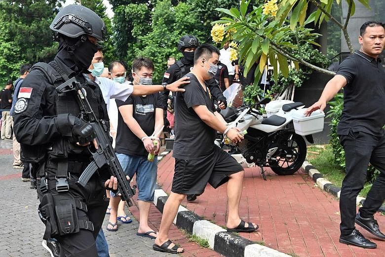 Indonesian police escorting a group of Chinese and Indonesian suspects in Jakarta yesterday. Dozens of Chinese nationals and six Indonesians were arrested over an online scam that bilked victims out of millions of dollars after the Indonesian police 