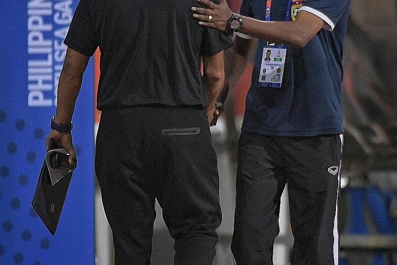 Left: Singapore's Zulqarnaen Suzliman getting in a shot against Laos in their SEA Games Group B opener at the Rizal Memorial Stadium in Manila. Below: Laos coach V. Sundram Moorthy is clearly the happier of the two as he shakes hands with Singapore c