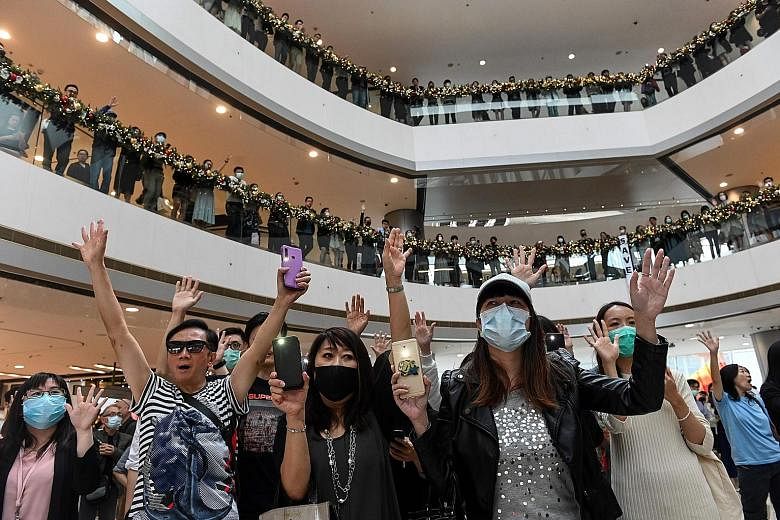 Workers showing support for pro-democracy protesters during a lunchtime rally at a mall in Central district yesterday. Pro-democracy candidates won almost 90 per cent of seats in district elections on Sunday. Riot police dispersing people during a pr