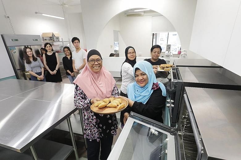 Madam Rusnah Sajee (centre, holding plate) with other women from the Bakers Beyond programme at their new baking facility in Whampoa Drive. Its commercial equipment such as convection ovens and chillers makes it easier to work on larger-scale project