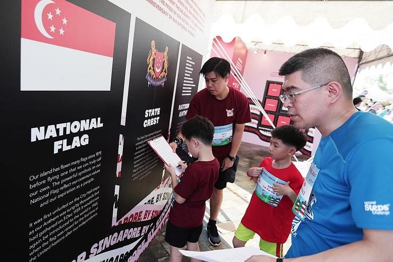 Families trying out quizzes that commemorate the 60th anniversary of Singapore's national symbols - the national flag, state crest and National Anthem - at the One Community Fiesta family sports carnival held at Jurong Lake Gardens yesterday. ST PHOT