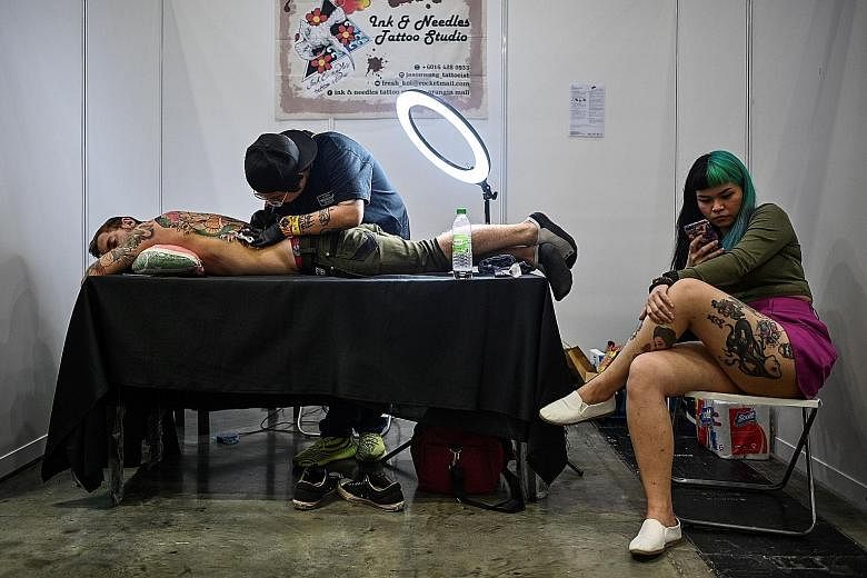 A tattoo artist working on a client during the Tattoo Malaysia Expo in Kuala Lumpur last Friday. The event was supported by Malaysia's Ministry of Tourism, Arts and Culture, according to the organiser's website. PHOTO: AGENCE FRANCE-PRESSE