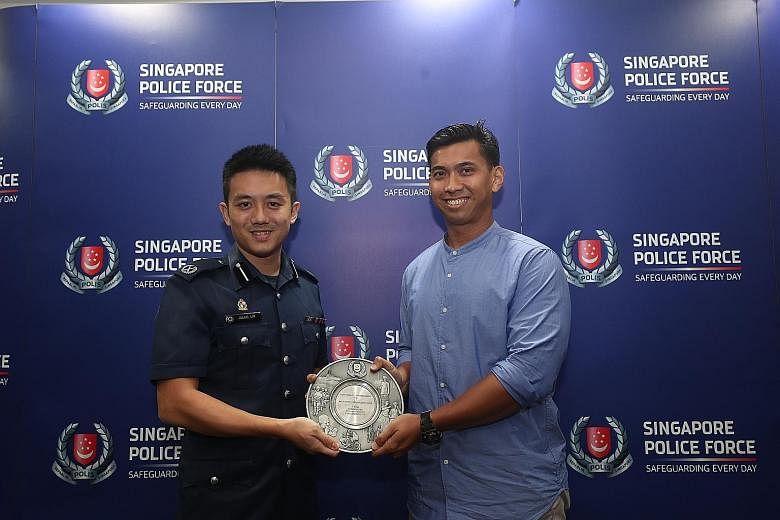 Commander of Bedok Police Division Julius Lim presenting the public spiritedness award to physical education teacher Khairil Anwar Tahir yesterday. Mr Khairil helped in the arrest of a man hitting passing vehicles with a hammer in Bedok North Road la