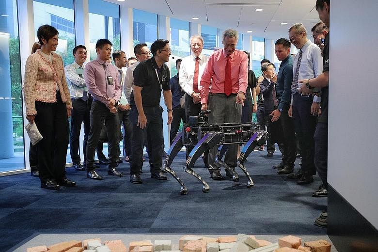 Prime Minister Lee Hsien Loong checking out a Rover-X robotic dog during the launch of the Home Team Science and Technology Agency yesterday, as Mr Ong Ka Hing (in black), deputy director for robotics at HTX's Autonomous Unmanned Systems Centre of Ex