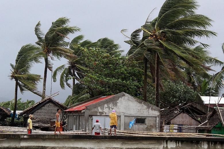 Strong winds blowing in the town of Calabanga in the Philippines' Camarines Sur province yesterday. Above: Filipino villagers getting off a truck as they evacuated their homes on Sunday in anticipation of the storm in Lagonoy town in Camarines Sur pr