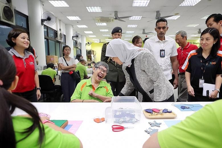 President Halimah Yacob with SPD trainee Lay Choo at the Sheltered Workshop in the SPD Ability Centre in Tiong Bahru yesterday. Also present was Keppel chairman Lee Boon Yang (right).