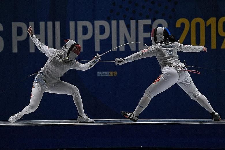 Amita Berthier (left) en route to defeating teammate Maxine Wong in the women's foil final yesterday to retain her gold. After receiving treatment for an ankle injury, she recovered from 10-9 down to win 15-10. ST PHOTO: MARK CHEONG