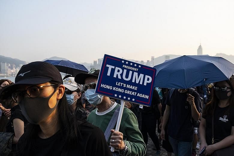 A demonstrator with a placard in support of US President Donald Trump during a protest in the Tsim Sha Tsui district of Hong Kong on Sunday. The city has been rocked by months of protests that were sometimes violent. They were sparked by a now-withdr
