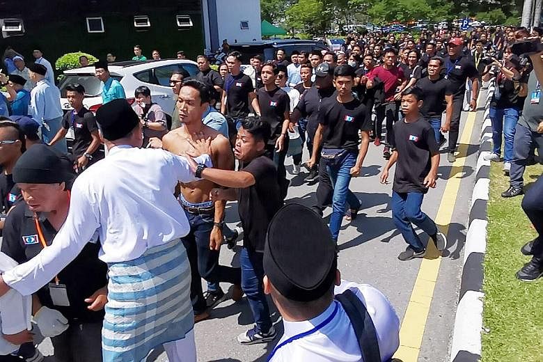 Scuffles broke out outside (above) and inside (below) the venue of the PKR's youth congress in Melaka yesterday morning, leading the pro-Azmin delegates in blue to skip the rest of the meet. A group of youths clad in black were seen at the Parti Kead