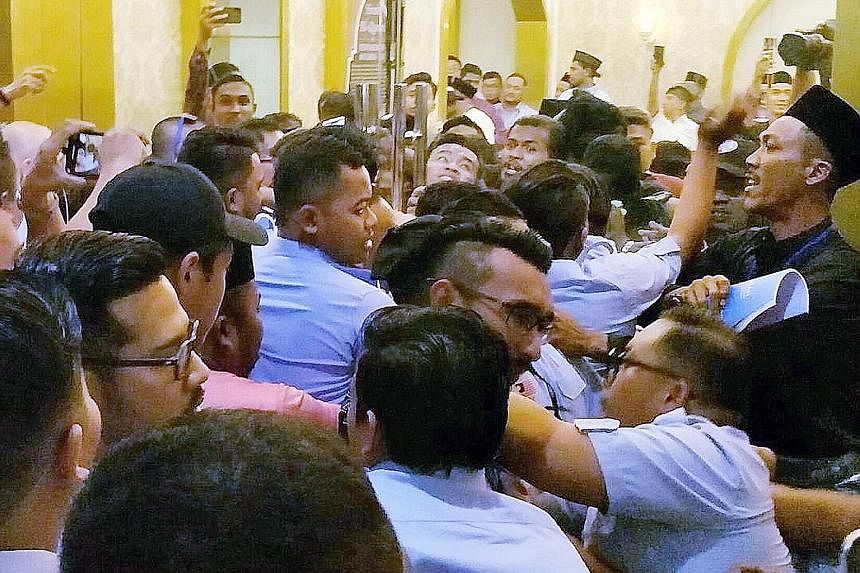Scuffles broke out outside (above) and inside (below) the venue of the PKR's youth congress in Melaka yesterday morning, leading the pro-Azmin delegates in blue to skip the rest of the meet. A group of youths clad in black were seen at the Parti Kead