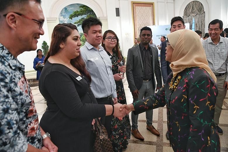 President Halimah Yacob meeting guests and award winners - including Ms Regina Cheah (fourth from left), who received an Environmental Services Star Award - at the Istana yesterday.