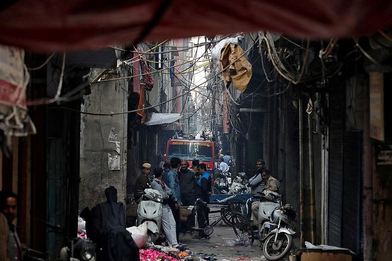 A fire engine at the site of a fire in central New Delhi that swept through a factory where labourers were sleeping yesterday. Firefighters had to fight the blaze from 100m away because it broke out in one of the area's many alleyways, too narrow for