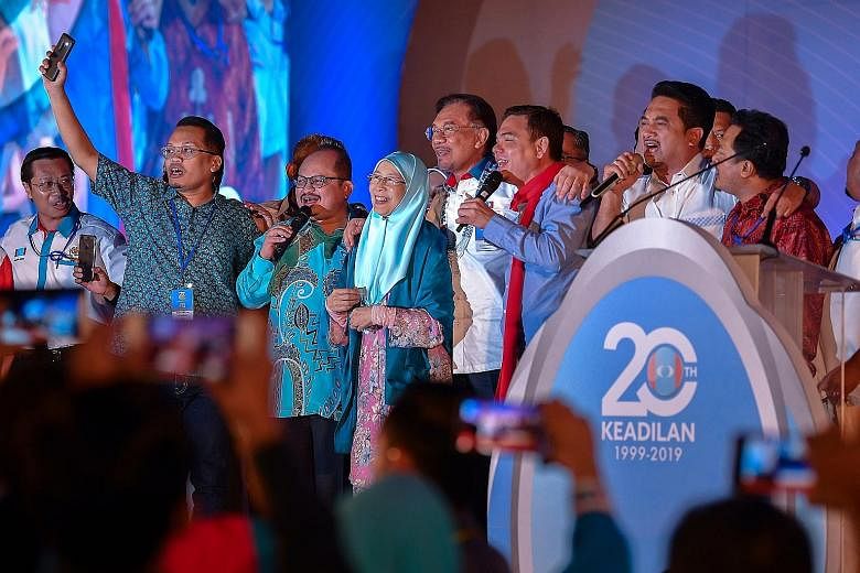 Parti Keadilan Rakyat president Anwar Ibrahim (centre, in white) with his faction's leadership team singing at the end of the party's annual congress in Melaka state. With him is his wife and chairman of PKR's board of advisers, Datuk Seri Wan Azizah