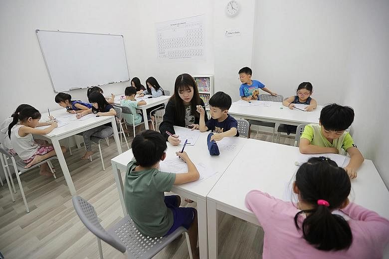 Tutor Calister Ng Jing Ni, 25, with pupils at EduFirst Learning Centre. Families spent about $1.4 billion last year on tuition for their children, according to the Household Expenditure Survey released in July. ST PHOTO: GIN TAY