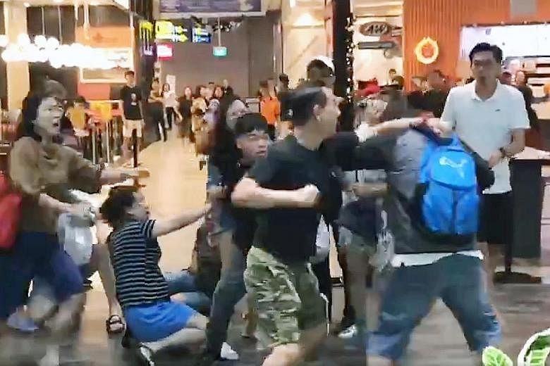 A screengrab of a video showing about 10 people, including women, involved in the brawl in front of fast-food chain A&W at Jewel Changi Airport on Sunday. PHOTO: