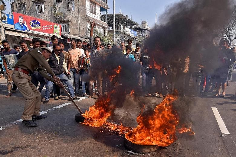 A policeman in Guwahati, India, removing tyres set ablaze yesterday by protesters during a rally against the Citizenship Amendment Bill, which seeks to give citizenship to refugees from three neighbouring countries - Afghanistan, Bangladesh and Pakis