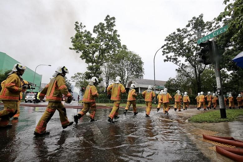 Singapore Civil Defence Force officers rushing to the scene of the fire in Tuas Crescent. Firefighters arrived on the scene within four minutes of SCDF being alerted to the blaze at 6am yesterday.
