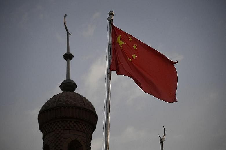 A Chinese flag beside a mosque in Xinjiang. While the US legislation is aimed at what it sees as human rights abuses in Xinjiang, China says its actions there are to fight poverty and religious radicalisation.
