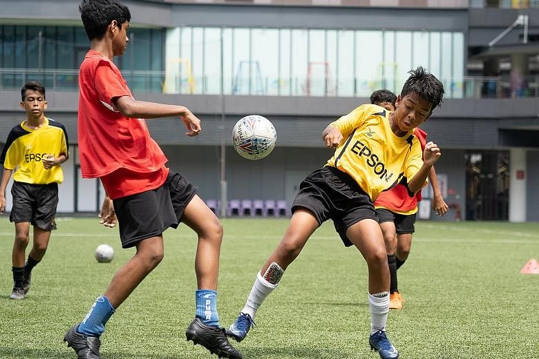 Hanan Hakimi (in yellow), 13, showing his tenacity while challenging for the ball during a practice match at Our Tampines Hub last week. The Tanjong Katong Secondary School student was a participant at a football clinic led by coaches from J-League s