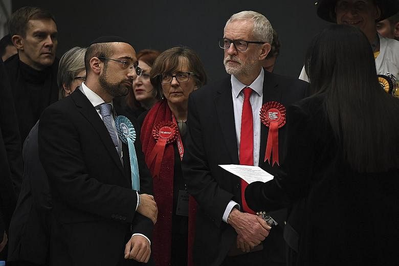 British opposition Labour Party leader Jeremy Corbyn (in red tie) waiting for his seat to be declared in the general election, in Islington, London, yesterday. He comfortably held on to his north London seat but called the party's worst electoral def