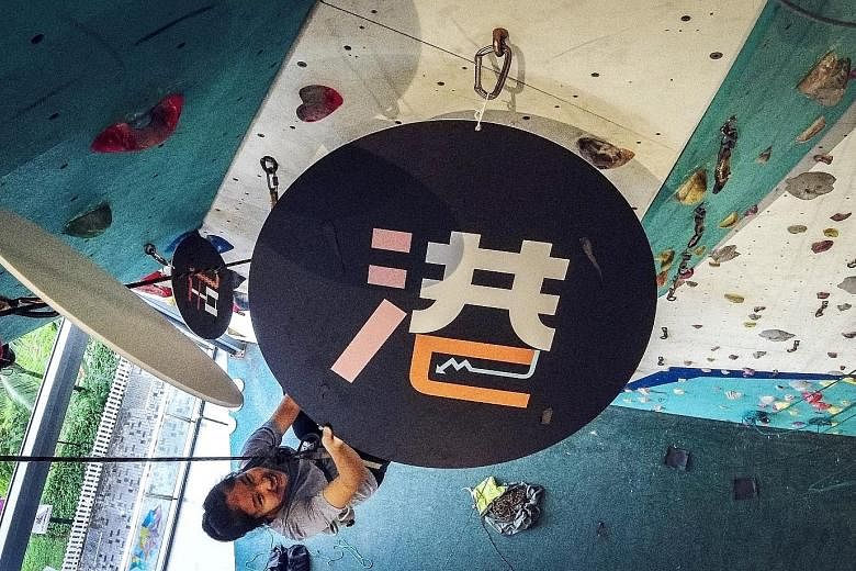 Rock climber Teo Rui Ern, 15, unveiling the Chinese word "gang" at The Rock School in Our Tampines Hub yesterday. An abbreviation of Hong Kong in Chinese, it was picked as word of the year by Lianhe Zaobao readers.
