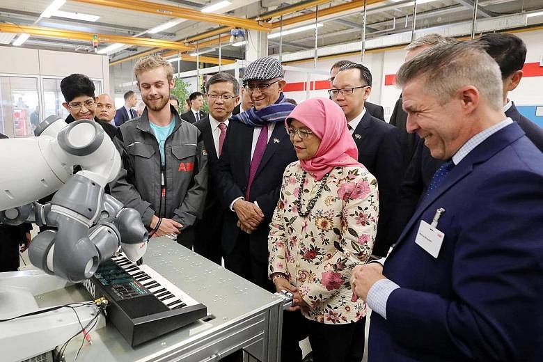 President Halimah Yacob watching a robotic arm in action during a visit to electrical equipment firm ABB Stotz in Heidelberg, Germany, on Thursday. She was accompanied by her husband, Mr Mohamed Abdullah Alhabshee, MP Fatimah Lateef and Senior Parlia