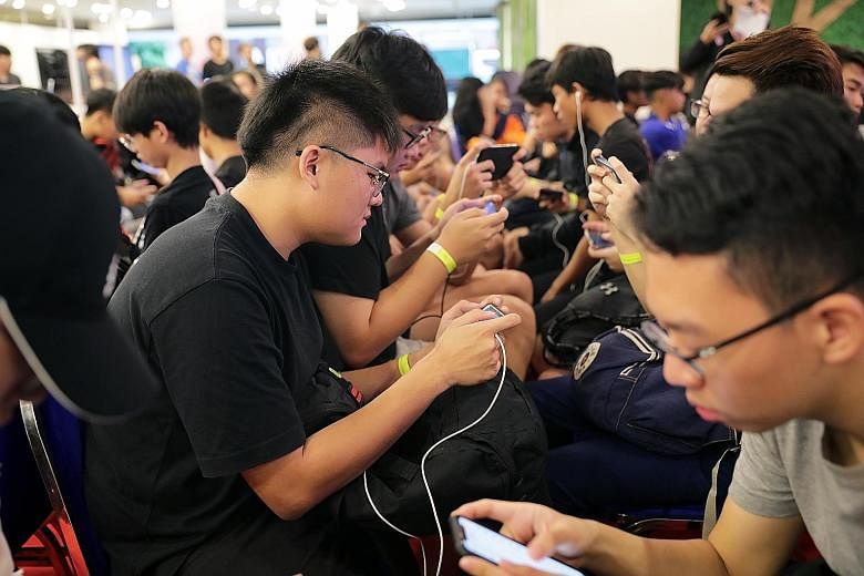 Full-time national serviceman Royden Lim (in black with yellow wrist tag on his left hand), 21, participating in an e-sports competition at Our Tampines Hub yesterday. He used to spend around 10 hours a day playing video games, but an argument with his pa