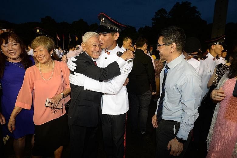 Former chief of defence force Winston Choo hugging grandson Daniel Choo at the commissioning parade yesterday, while son Warren Choo looks on. PHOTO: LIANHE ZAOBAO