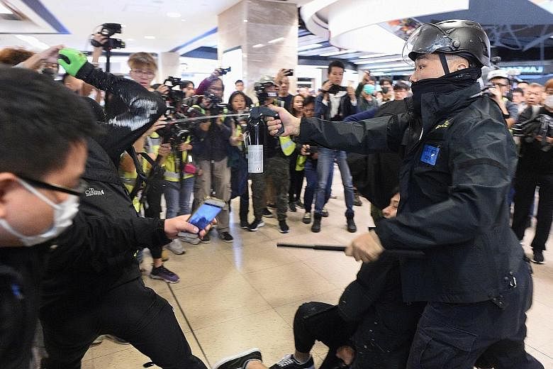 A policeman using pepper spray on a demonstrator during clashes at New Town Plaza in Shatin yesterday. Scuffles also broke out at Telford Plaza in Kowloon Bay.
