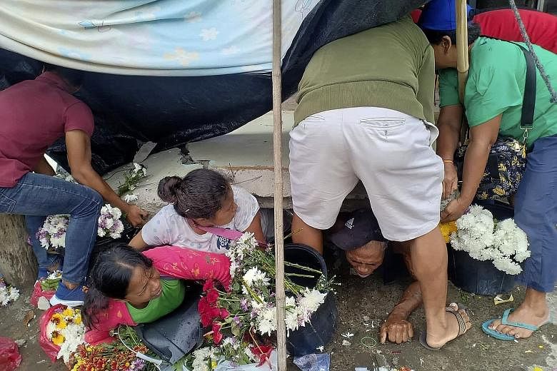 Trapped flower vendors being pulled out from under a collapsed wall following a magnitude-6.8 earthquake that struck the southern Philippines yesterday. The earthquake caused a three-storey building to collapse, setting off a search for people feared