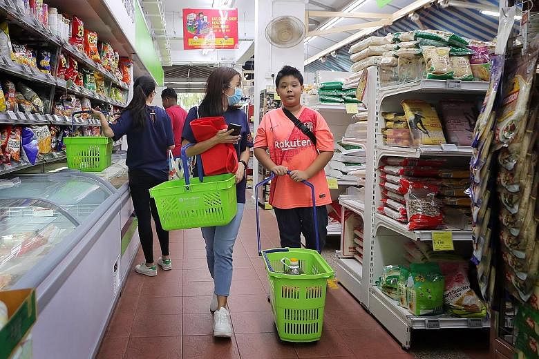 Mewah employee and volunteer Charen Lim helping Clementi Primary School pupil Muhammad Khairunnas, 12, choose groceries at Sheng Siong supermarket in Clementi earlier this month. The Fresh programme by Children's Wishing Well organises weekly superma