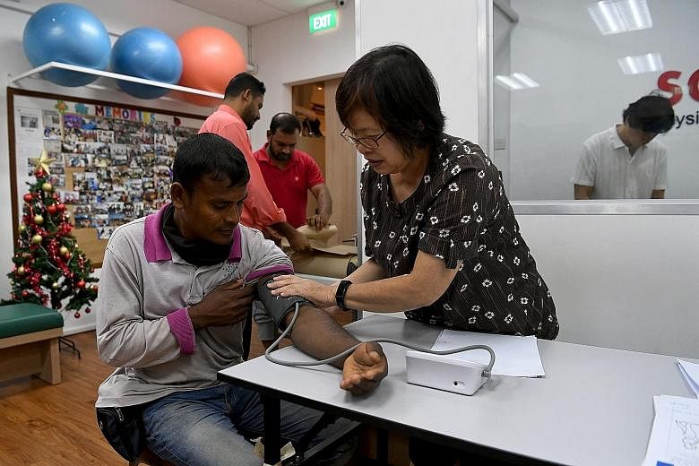 A volunteer attending to a migrant worker at SG Accident Help Centre in Flanders Square. The centre has about 20 volunteer physiotherapists and traditional Chinese medicine physicians, who provide their services at its premises or in foreign worker d