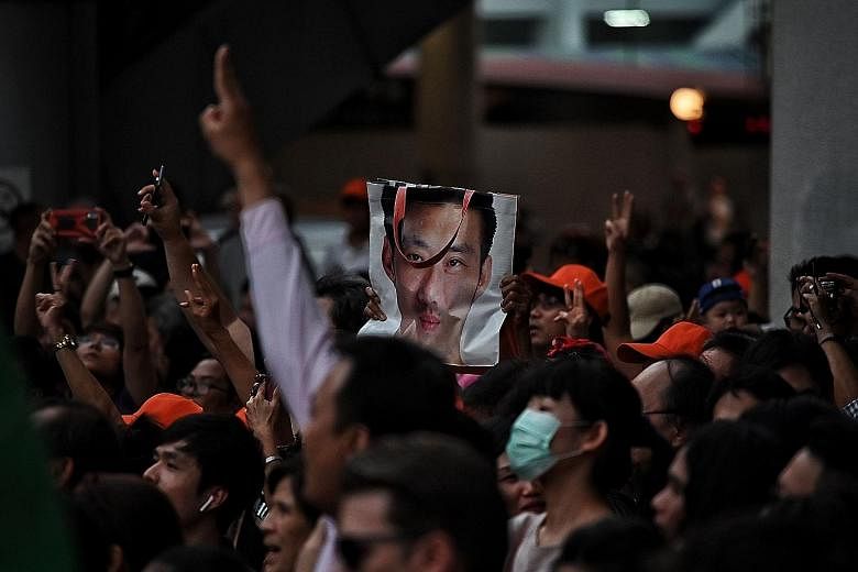 (Above) A protester at a Bangkok rally last Saturday holding a bag with a photo of Future Forward leader Thanathorn Juangroongruangkit. Thousands had gathered to show support for the party.