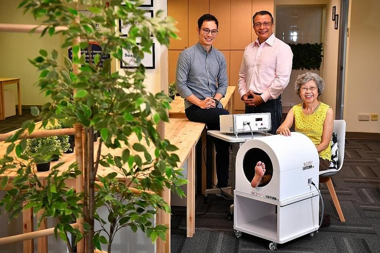 Retiree Maureen Swee on the Biceps machine at the Centre for Innovation in Healthcare co-working space, with QuantumTX CEO Ivan Goh (far left) and NUS Associate Professor Alfredo Franco-Obregon. Ms Swee, who used to lean on her umbrella while climbin