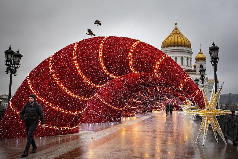 People walking along Moscow's Patriarch's Bridge, which is all decked out for Christmas and New Year, with Christ the Saviour Cathedral in the background. Christmas in Russia is normally celebrated on Jan 7 (only a few Catholics celebrate it on Dec 25). T