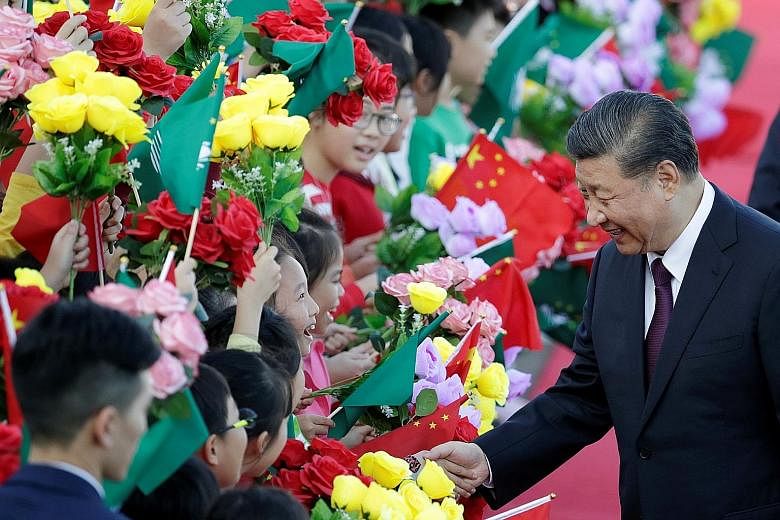Chinese President Xi Jinping greeting children holding Chinese and Macau flags on arrival in Macau yesterday, ahead of the 20th anniversary of the former Portuguese colony's return to China. During his three-day visit, Mr Xi is expected to announce a