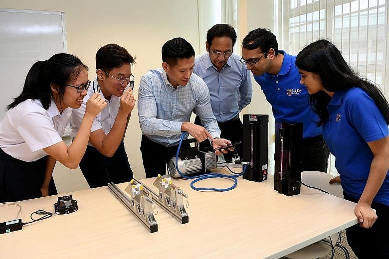 Jurong Pioneer Junior College's head of department for curricular development and innovation Edwin Lim using a mobile phone spectrometer, which measures light wavelengths. With him (from far left) are students Narahda Lim and Haw Jin Yu; Professor Th