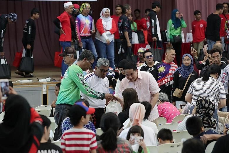 Senior Parliamentary Secretary for Home Affairs and Health Amrin Amin (centre) helping to give out food bags at Woodlands Community Club yesterday. Volunteers at the event included members of 23 motorcycle groups.