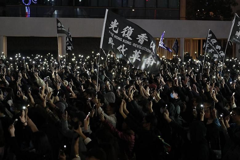 Protesters shining lights from cellphones and raising their hands to symbolise the pro-democracy movement's five demands at a rally in Hong Kong yesterday. PHOTO: ASSOCIATED PRESS