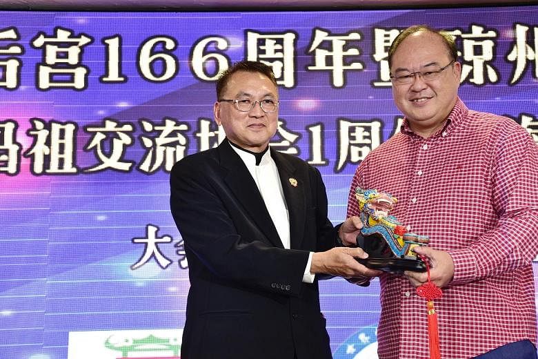 Kheng Chiu Tin Hou Kong and Burial Ground chairman Foo Jong Peng (left) presenting a memento to Mr Tan Aik Hock, president of the Singapore Federation of Chinese Clan Associations, during the launch of the Hainan Federation yesterday.