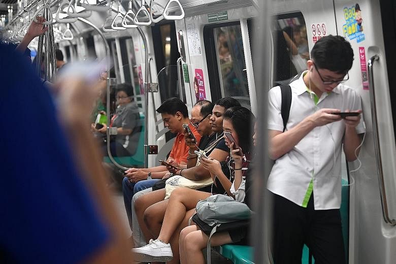 Top: MRT commuters using smartphones. Next year, Singapore will issue licences for up to four 5G networks instead of the original two, as it takes bolder steps to embrace a technology seen as crucial to its economic growth.