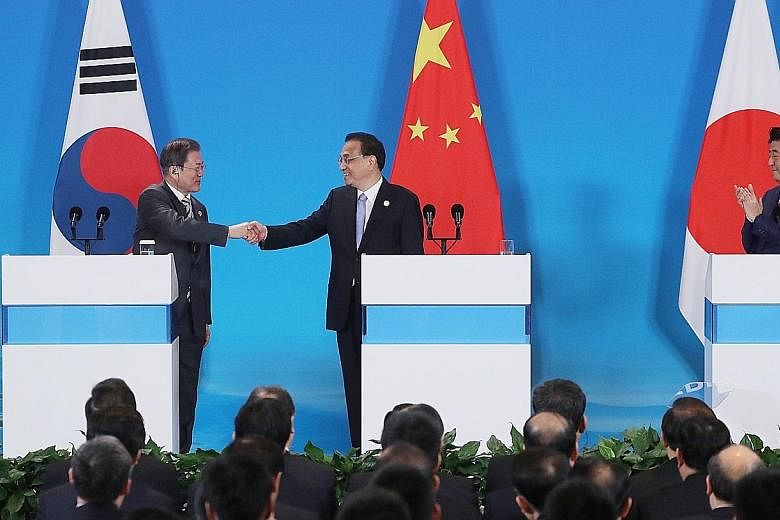 South Korean President Moon Jae-in shaking hands with Chinese Premier Li Keqiang as Japanese Prime Minister Shinzo Abe looked on during a joint press conference after a trilateral summit in Chengdu, China, yesterday. The meeting between Mr Moon and M